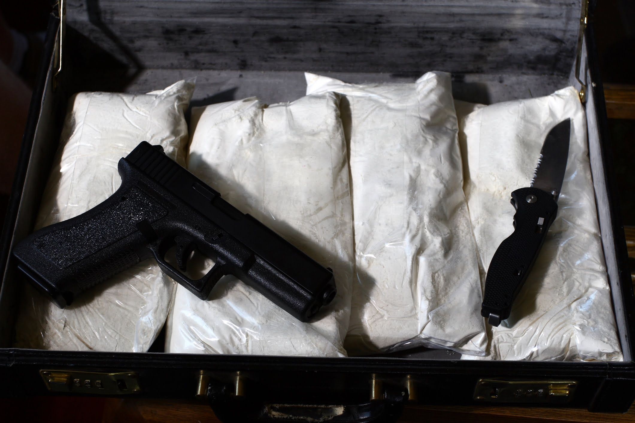 Top Vista & San Diego Drug Distribution and Trafficking Attorney 1 A suitcase with bags of white powder and weapons to illustrate content for a Vista and san diego Drug Transportation Lawyer