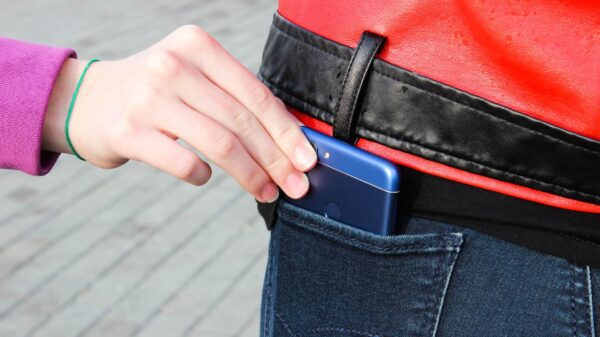 A woman stealing a cell phone from a man's pocket