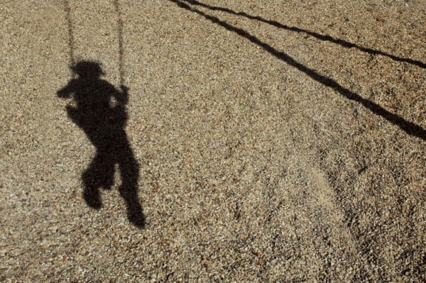 Sombra de niño balanceándose en un columpio
