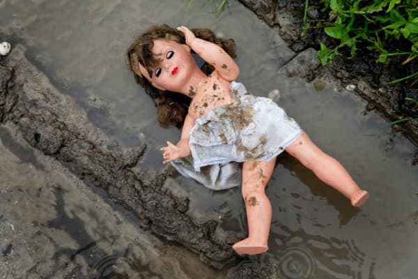288 (PC) illustration depicting a doll in the mud with her clothes pulled half off
