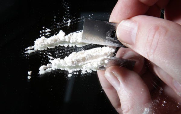 ABOGADO DE DROGAS EN VISTA Y SAN DIEGO 10 Una persona cortando cocaína con una cuchilla de afeitar.