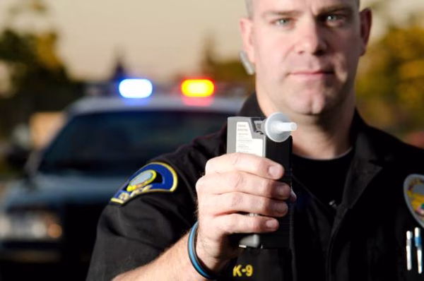 A police officer holding a breath testing device to illustrate what BAC measures